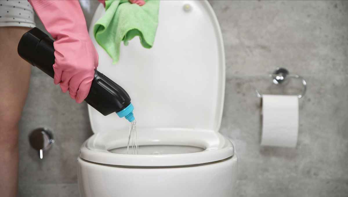 Woman pouring bleach down a toilet